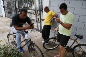 Cubans check their phones outside a center run by a Havana artist who offers his Wi-Fi network for free [Image Courtesy of Wall Street Journal]